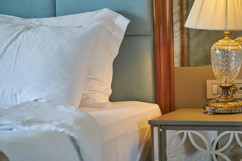 Lit d’hôtel avec coussins et lampe sur une table de chevet