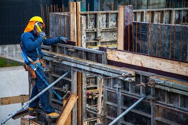 Ouvrier équipé d’un casque et d’un harnais sur un coffrage de chantier