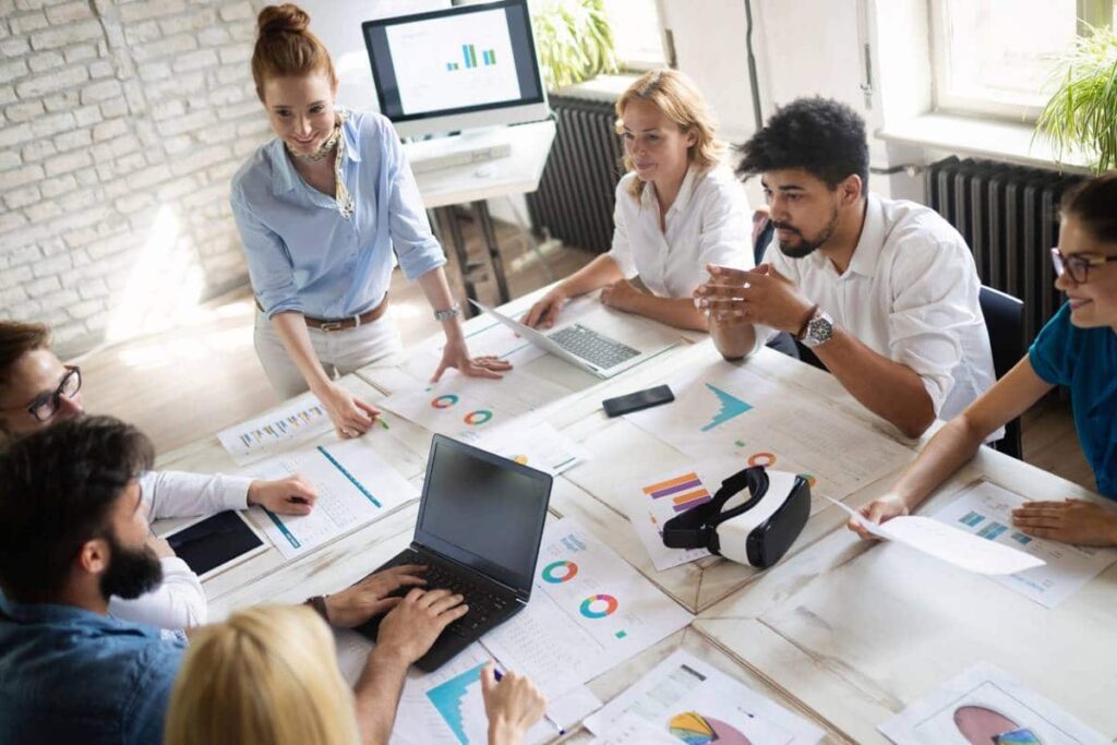Équipe réunie autour d'une table couverte de graphiques et d'ordinateurs
