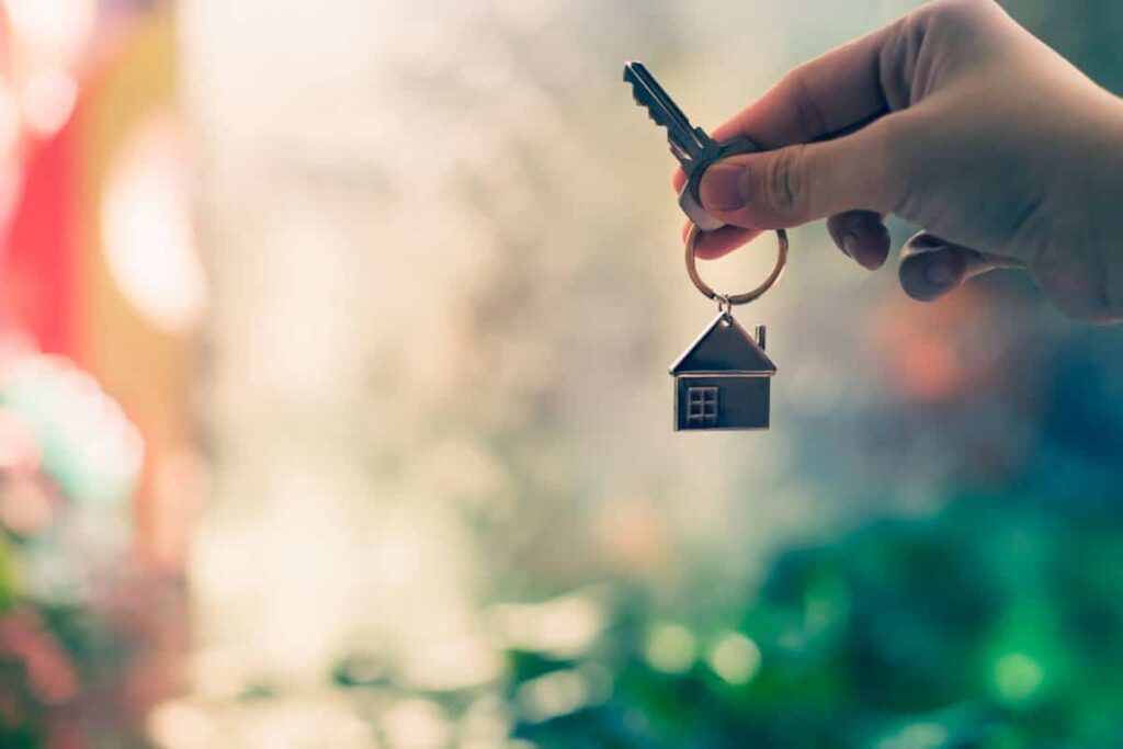 Main tenant une clé avec un porte-clés en forme de maison