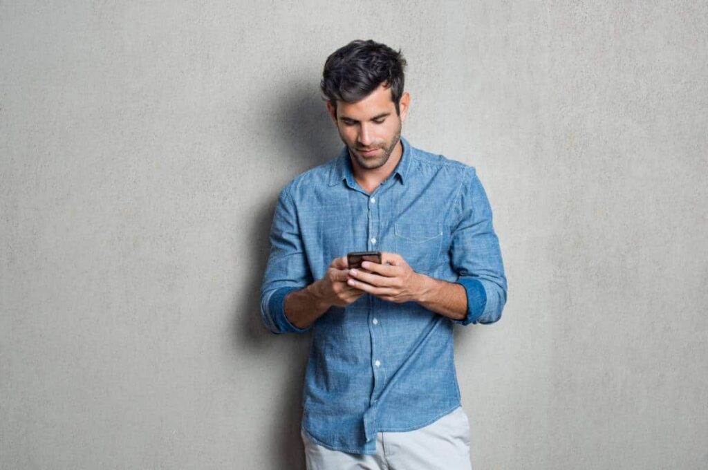 Homme adossé à un mur consultant son téléphone