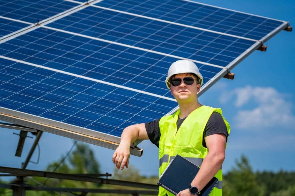 Technicien en gilet de sécurité devant des panneaux photovoltaïques