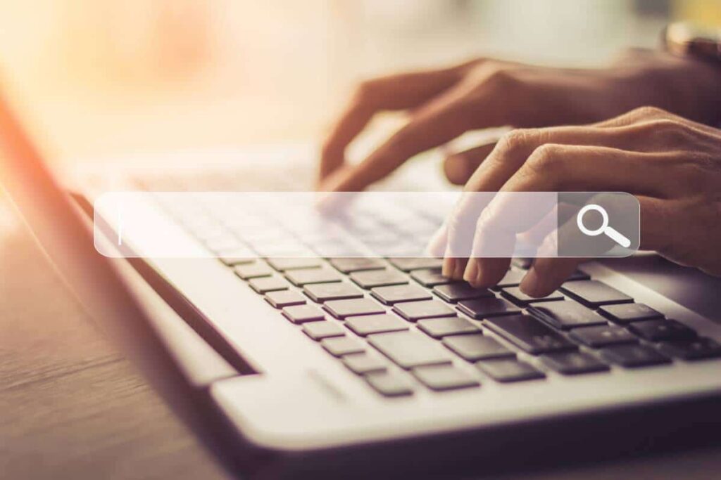Mains tapant sur un clavier avec une barre de recherche en surimpression