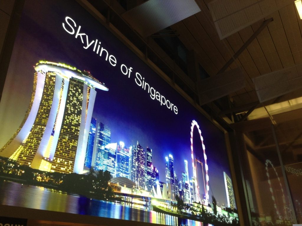 Grand écran publicitaire lumineux affichant une vue nocturne de Singapour