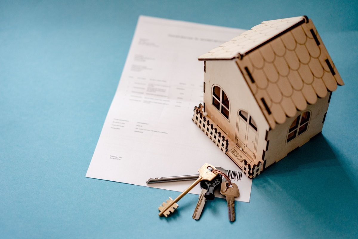 Maquette de maison posée sur un document avec des clés
