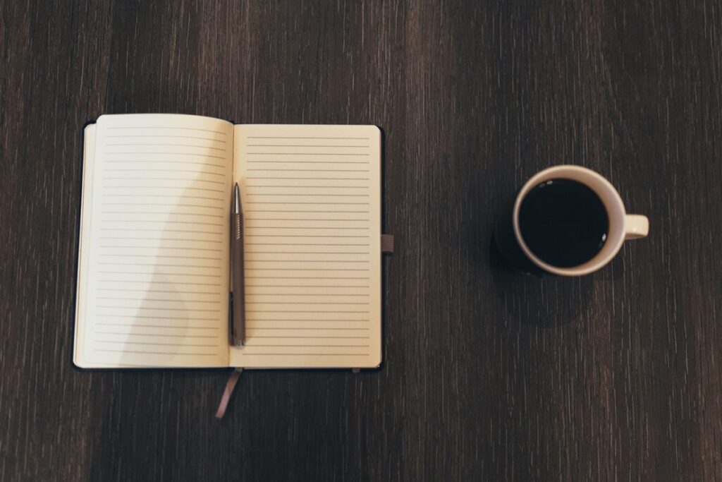 Carnet ouvert et stylo posés sur un bureau en bois